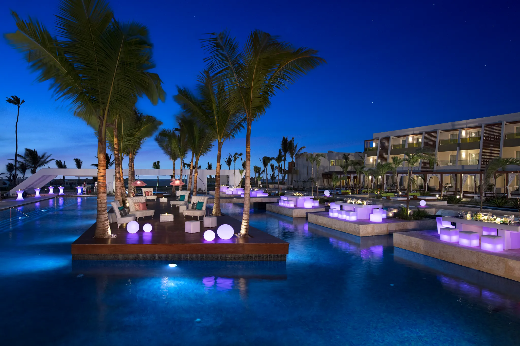Poolside gala dinner setup with glowing decor and lounge seating at Dreams Onyx Resort & Spa at night