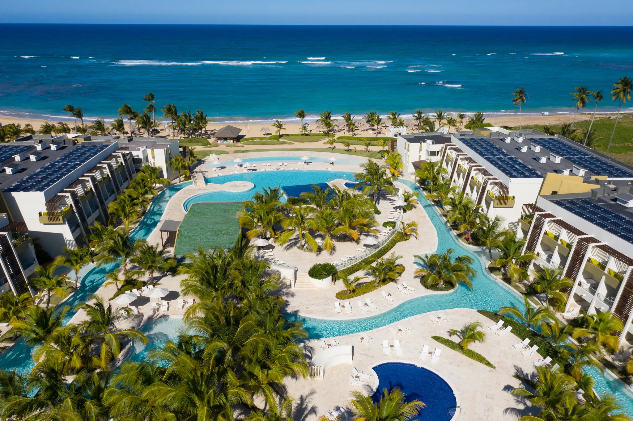 Aerial view of large resort pool surrounded by palm trees at Dreams Onyx Resort & Spa.